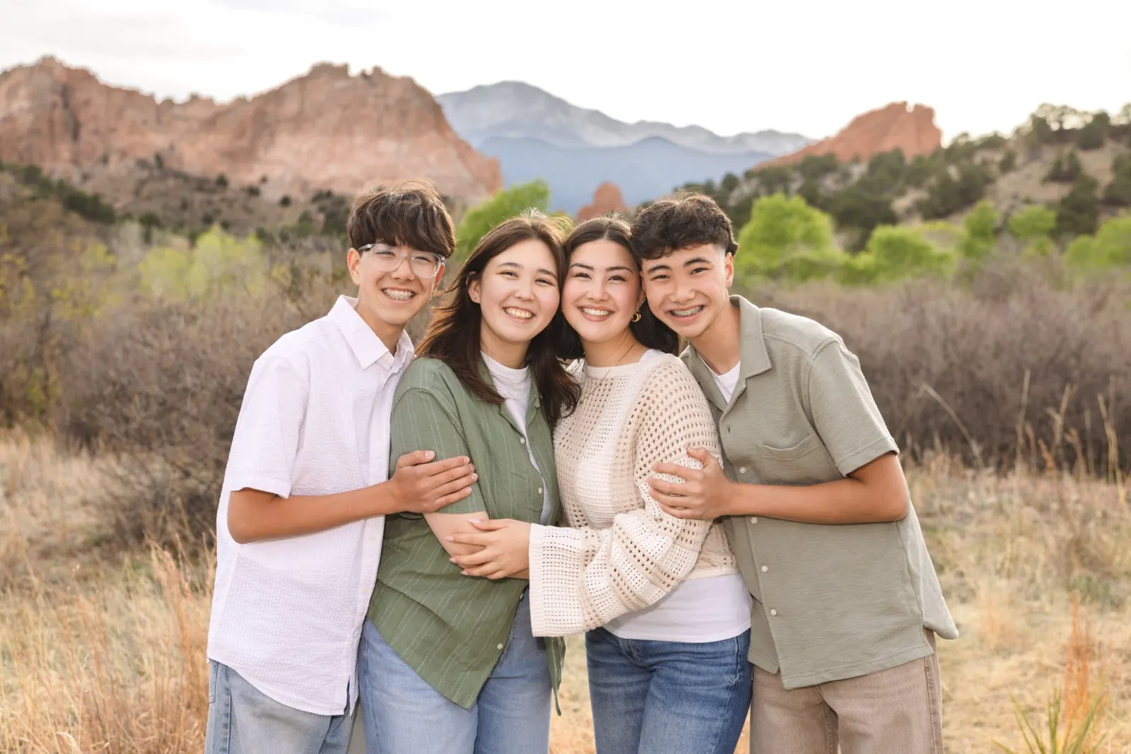 Liliana, Amiella, Teo and Jaden arm in arm, with red rocks and mountains in Colorado Springs behind them