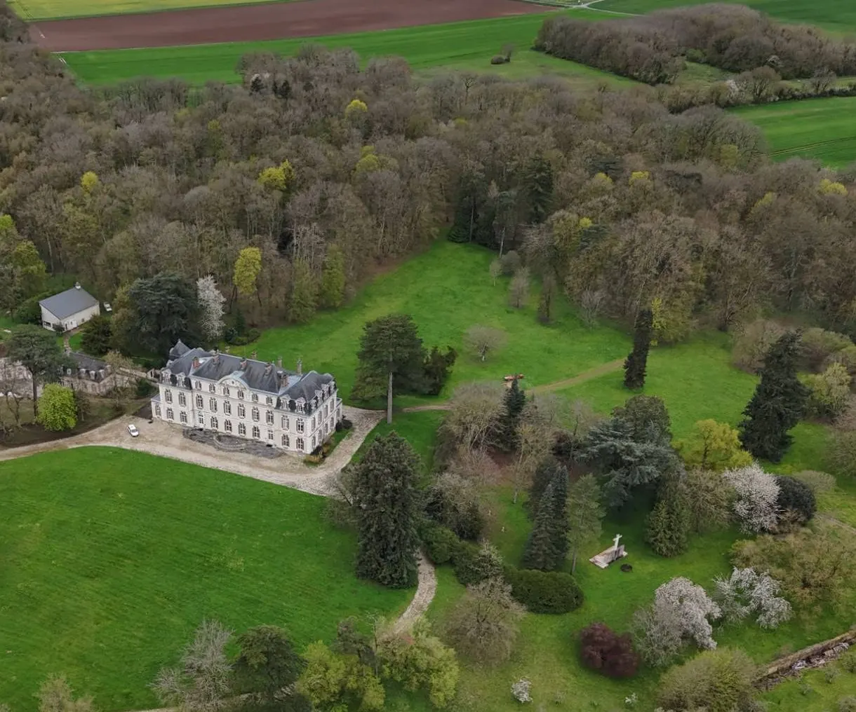 Aerial view of a white château among trees and lawns in France